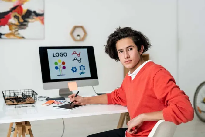 Young Serious Web Designer With Stylus Graphics Tablet Sitting By Desk Front Camera Home Environment X - Adobe Certified Associate study guide