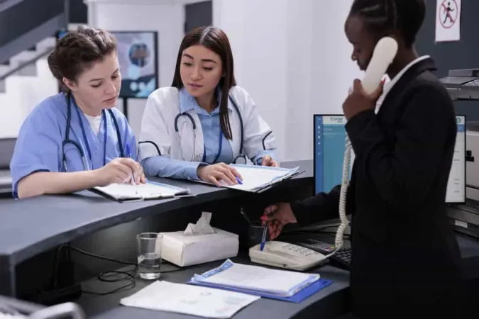 Hospital Reception Worker Talking Landline Phone Being Responsible Scheduling Appointments Managing Patient Records Nurse Doctor Looking Papers With Medical Expertise Lobby X - Certified Health Service Administrator study guide